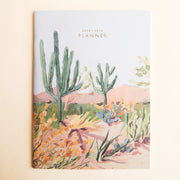 On a tan background is a cardstock planner with a beautiful desert scape illustration on the front along with small text at the top that reads, "2023-2024 Planner".