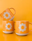 A yellow ceramic mug with a flower shape in the center.