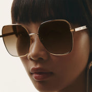 A oversized pair of gold metal frame sunglasses with brown lenses.