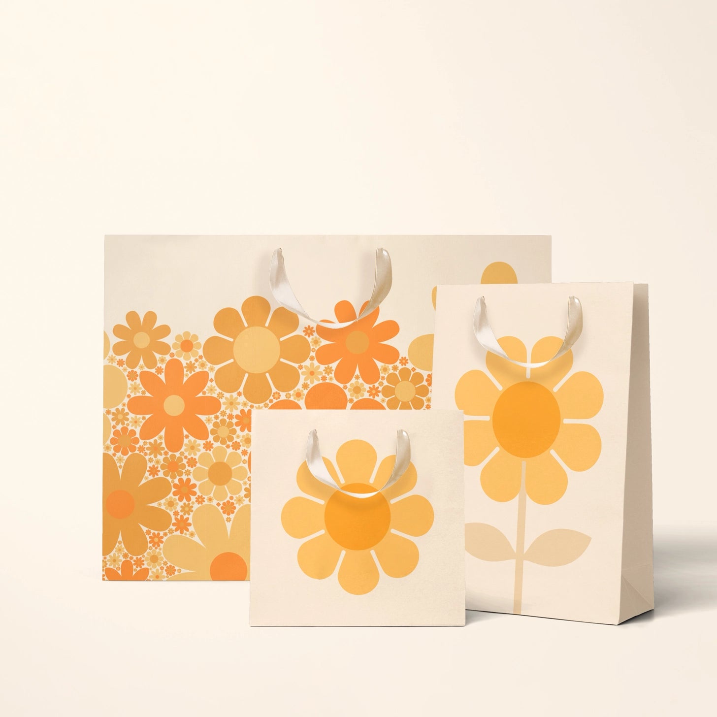 On a cream background is three different sized ivory gift bags with orange and yellow daisy patterns. 