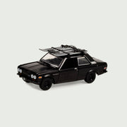 Black Datsun 510 toy car with roof rack holding skiis.