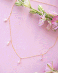A dainty gold chain necklace with five freshwater pearls hanging spaced out on the chain.