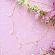 A dainty gold chain necklace with five freshwater pearls hanging spaced out on the chain.