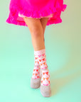 A pair of light pink socks with red, orange and pink bow patterns all over.
