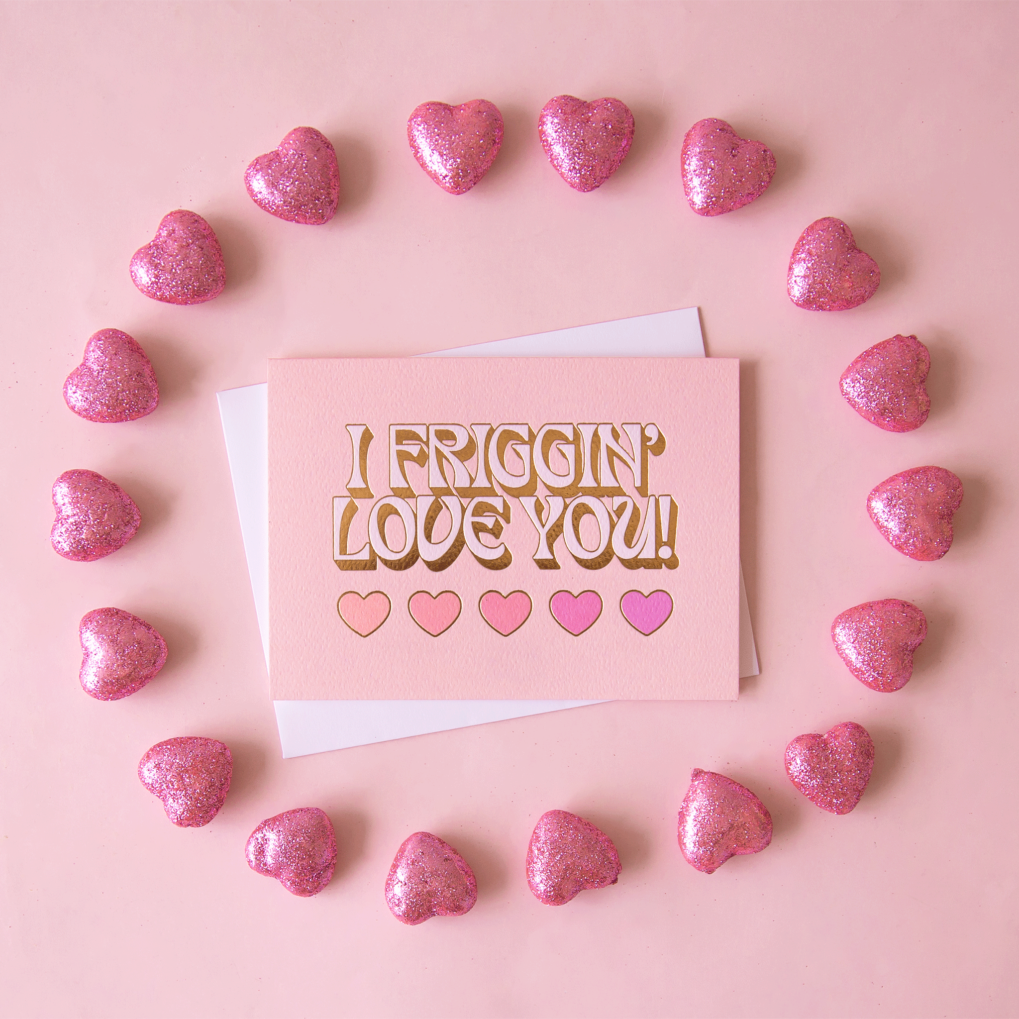 On a pink background is a light pink card with text that reads, &quot;I Friggin&#39; Love You!&quot; with five hearts underneath.