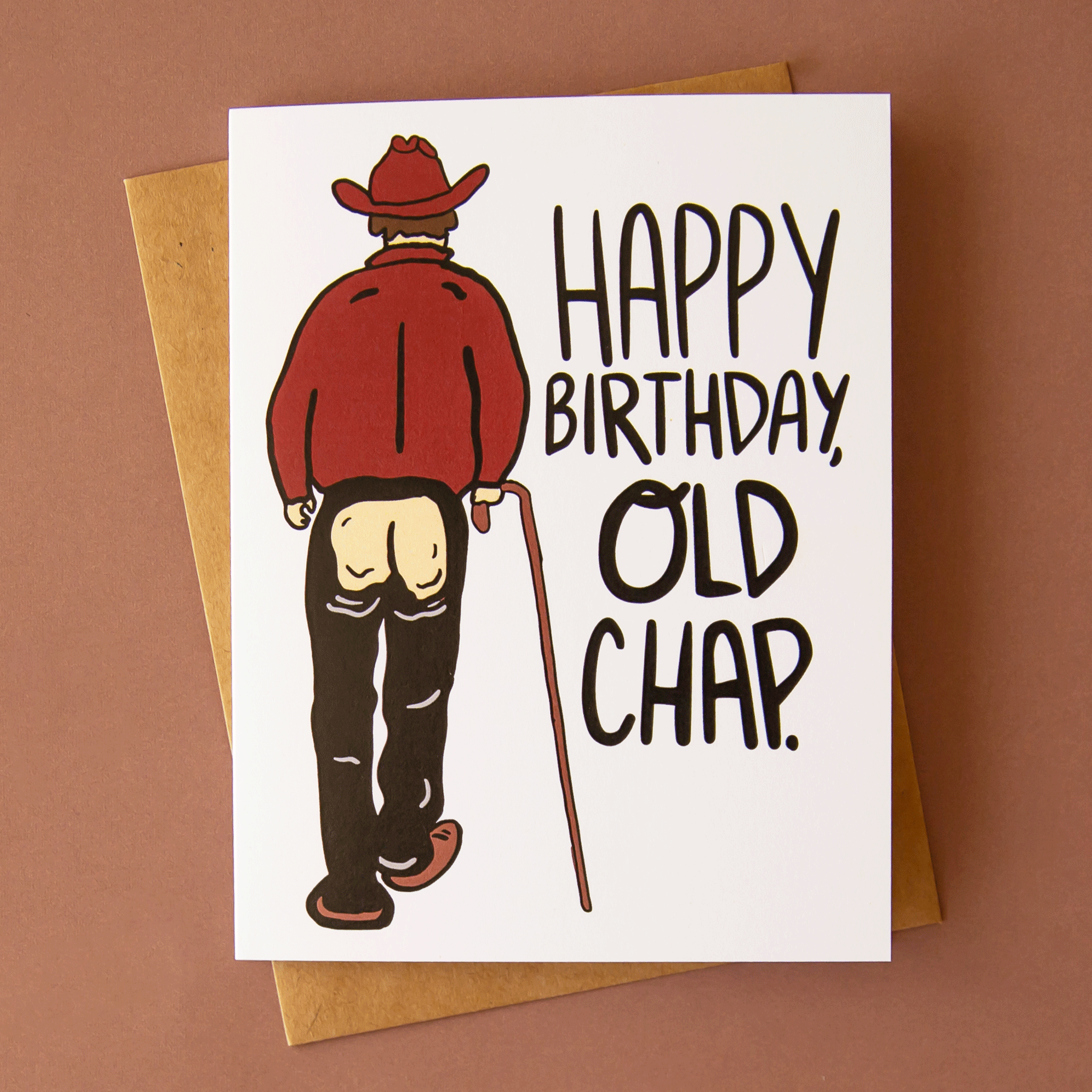 On a brown background is a white card with an illustration of a cowboy with chaps on and an open bottom area along with black text to the right that reads, &quot;Happy Birthday Old Chap&quot;.