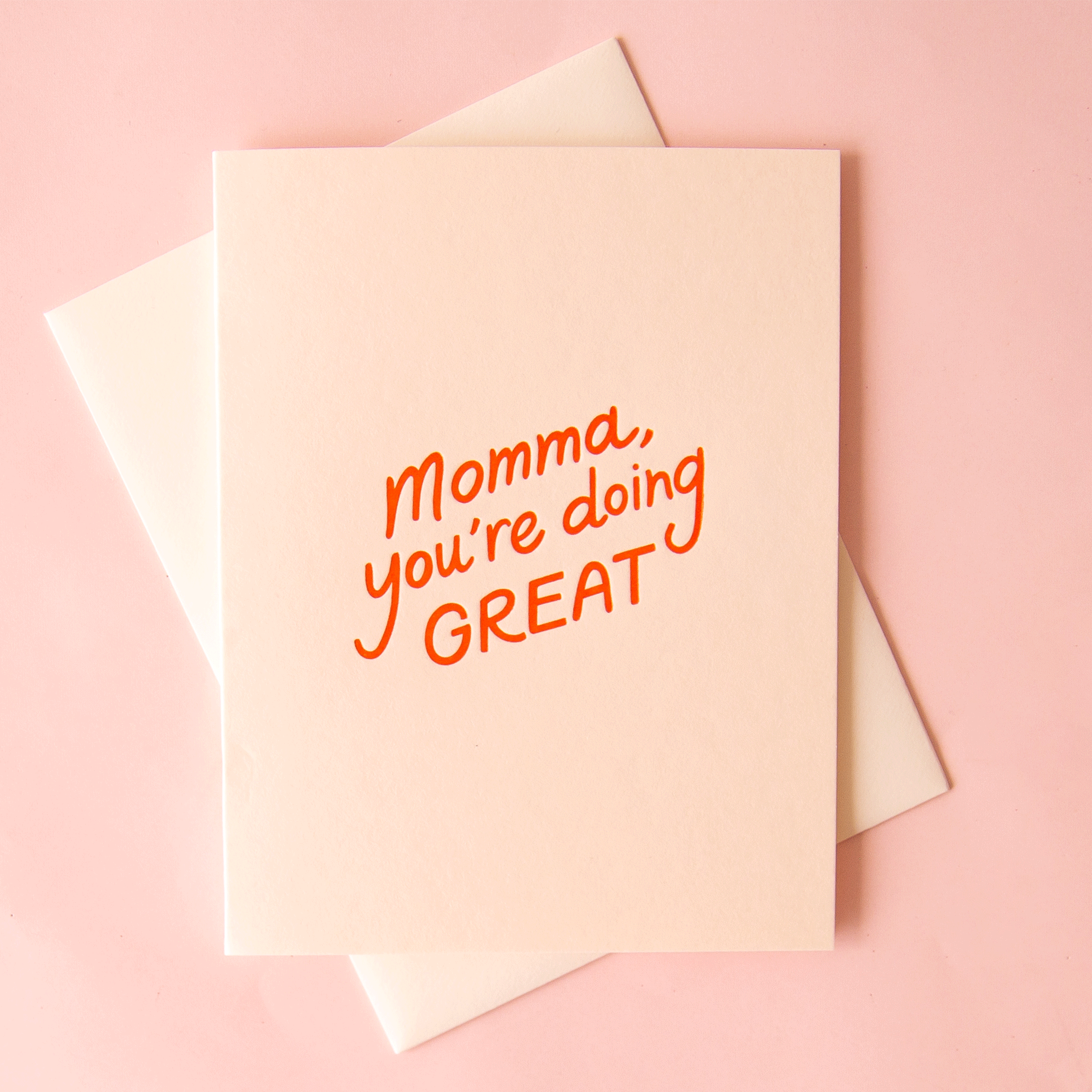 On a pink background is a light ivory card that reads, "Momma, you're doing GREAT" in red letters.