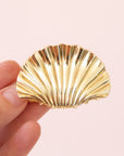 A gold seashell shaped hair clip.