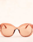 A light brown translucent pair of sunglasses that have a rounded shape and a light brown lens.