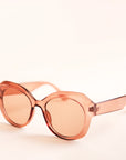 On a white background is a light brown translucent sunglasses that have a rounded shape and a light brown lens.