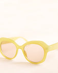 On a white background is a round pair of light green sunglasses with a light brown lens..