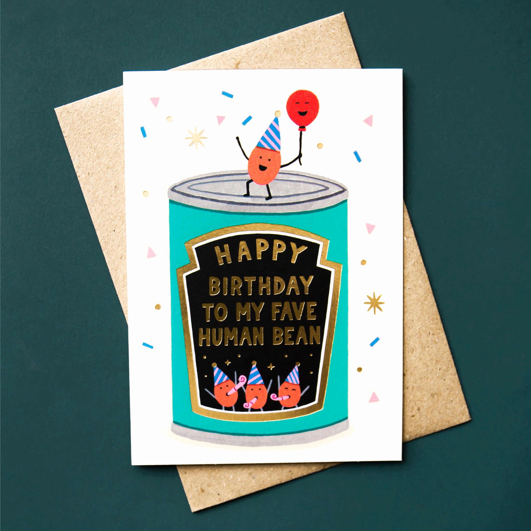 On a teal background is a white card with a graphic of a can of beans along with gold foiled text that reads, "Happy Birthday To My Fave Human Bean" and beans with smiling faces and party hats. 