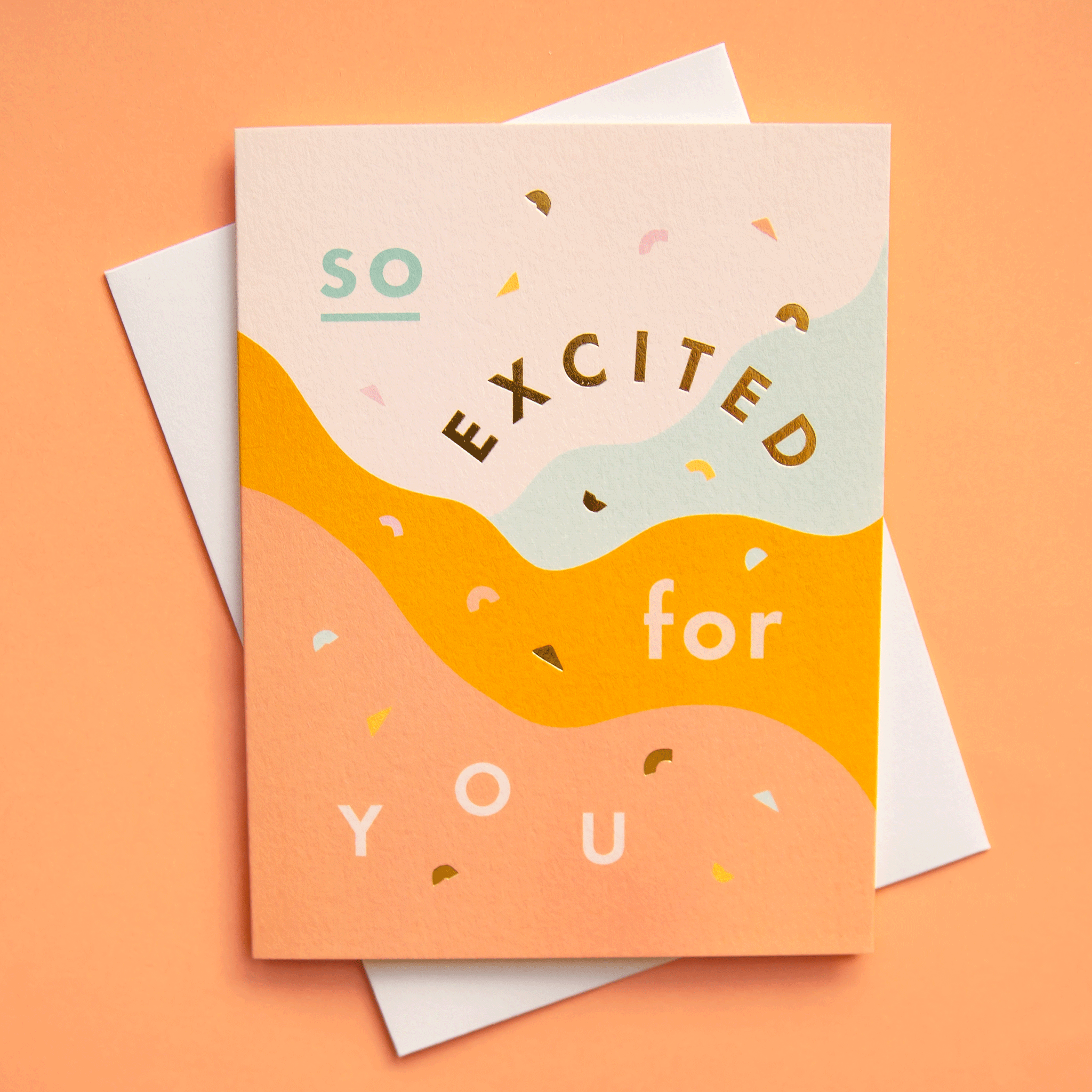 On a white background is a multicolored card with waves that reads, &quot;So Excited for You&quot; in different colored text.