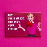 On a pink background is a pink magnet with a vintage graphic of a woman in a pink sweater and white text that reads, "Hey, Train Wreck This Isn't Your Station.".