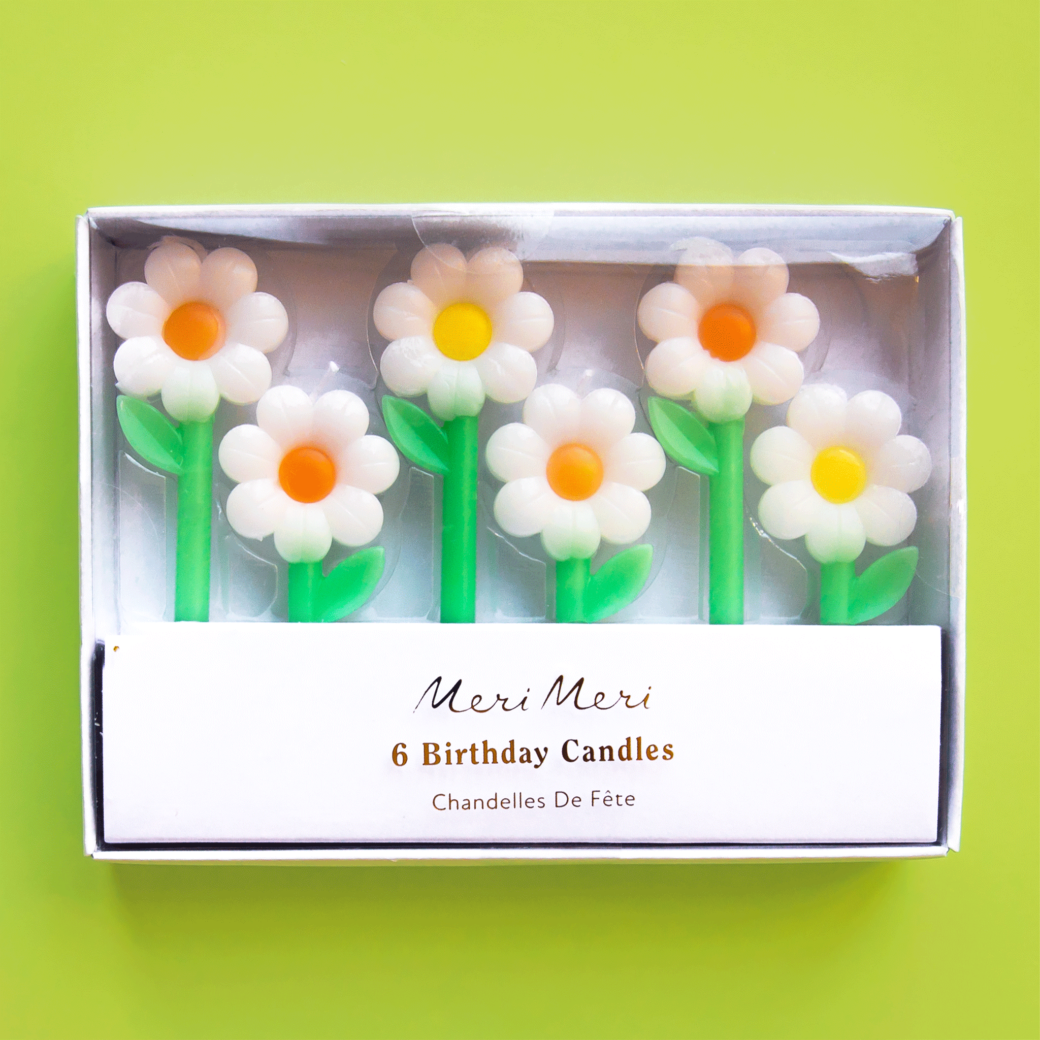 On a green background is a pack of daisy shaped candles in two different sizes.