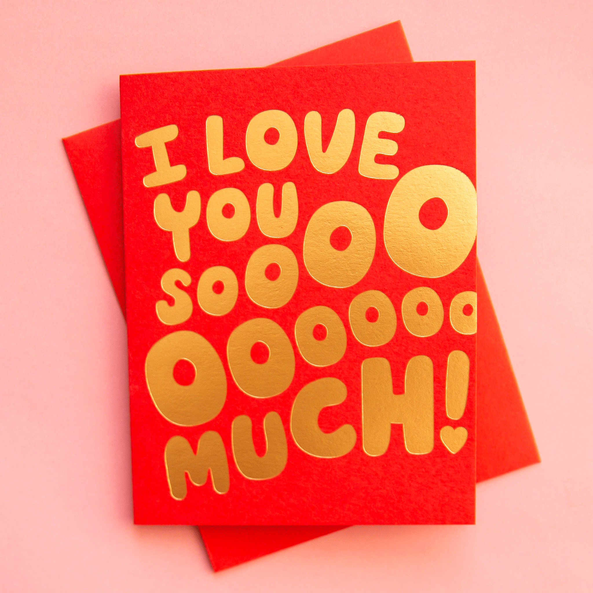 On a pink background is a red card with gold foiled text that reads, "I Love You Sooooo Much!. 