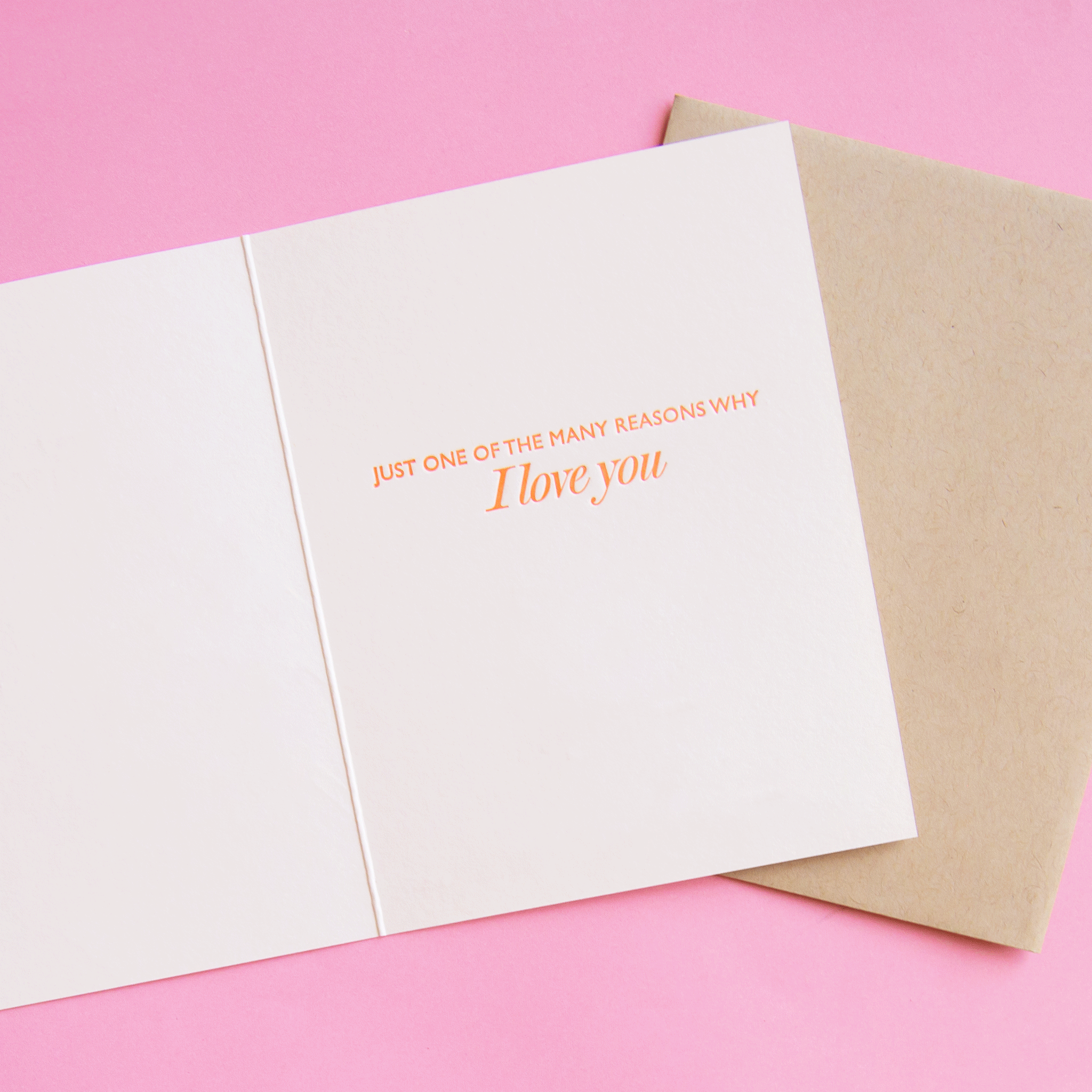 On a pink background is a white card with text inside that reads, "Just One Of The Many Reasons Why I Love You". 