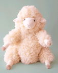 On a blue background is an ivory fluffy sheep stuffed animal toy.