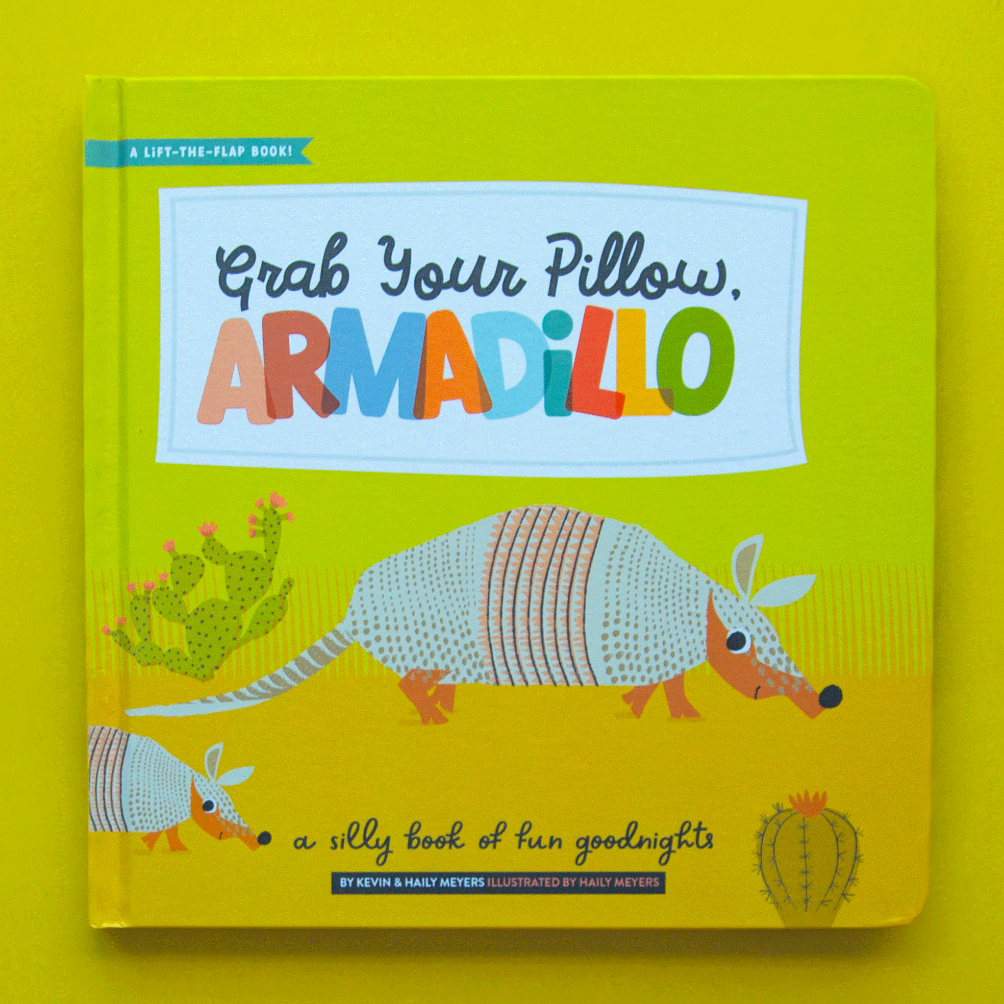 On a neon green background is a neon book cover with an illustration two armadillos with the title above that reads, &quot;Grab Your Pillow Armadillo&quot;. 