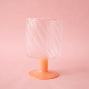 A wavy glass wine glass with a pink short stem.