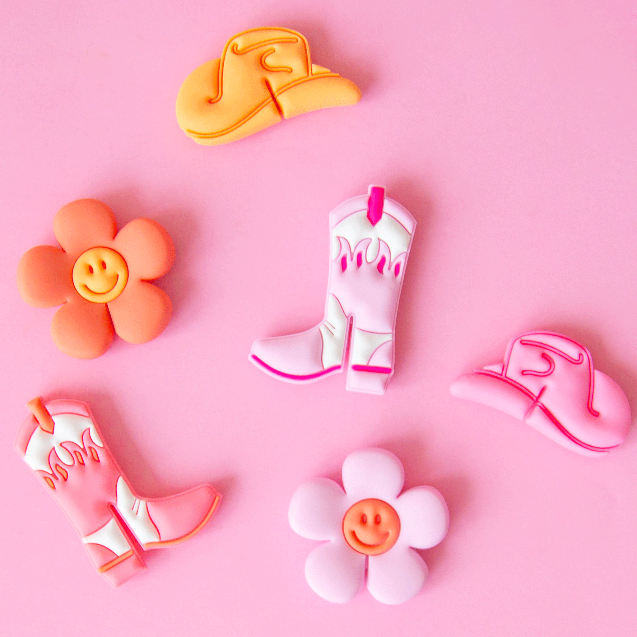 On a pink background is a set of 6 drink markers in western themed shapes including cowgirl boots, hats and smiley face daisies.