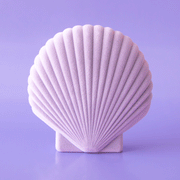 On a purple background is a purple plastic and velvet jewelry / storage box in the shape of a sea shell.