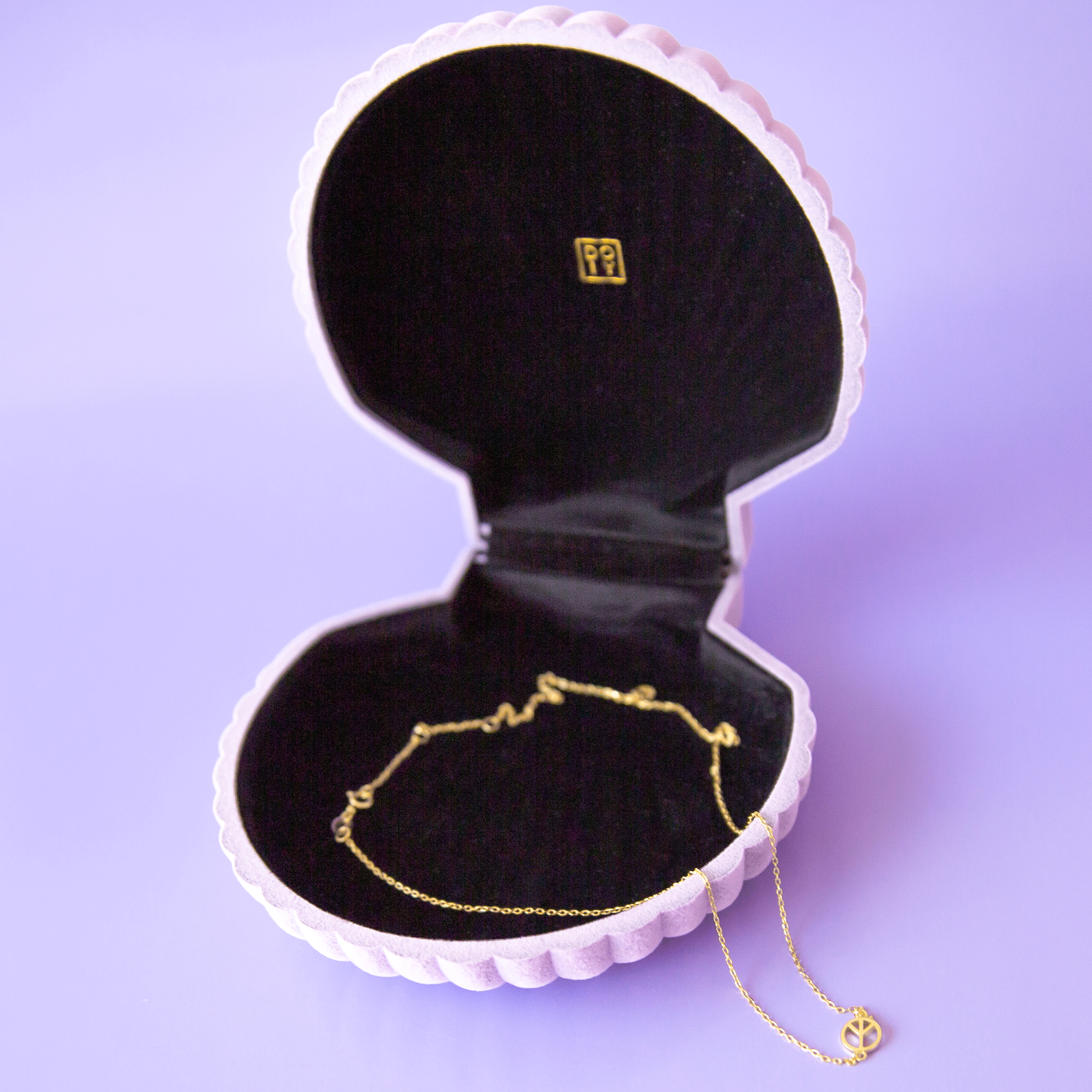 On a purple background is a purple velvet seashell shaped jewelry box with a necklace inside that is not included with purchase.