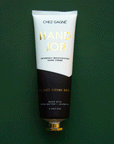 On a dark green background is a tube of hand cream that is half black and half white along with gold text that reads, "Hand Job" as well as black text underneath that reads, "Intensely moisturizing hand crème.