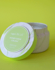 On a green background is a green and white marble tin candle with a lid that reads, "capri Blue Honeydew Crush".