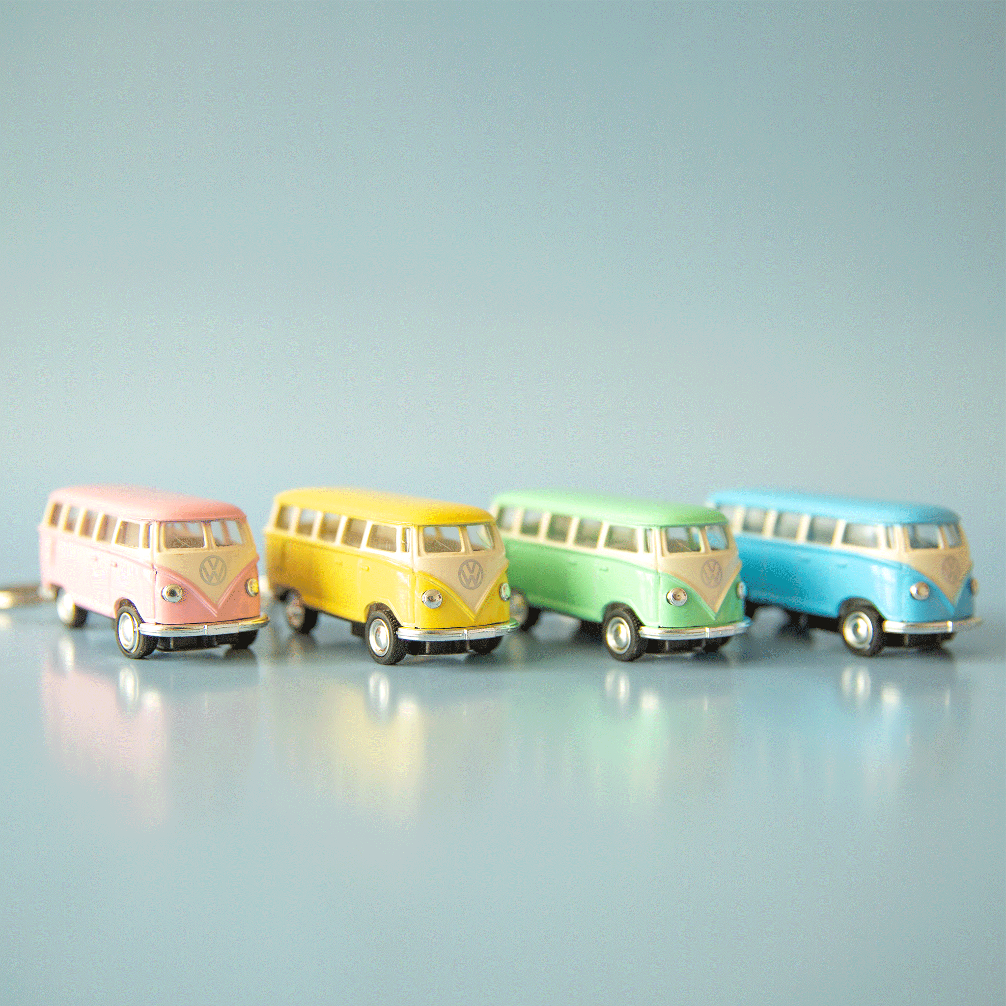 On a blue background is four VW bus shaped keychains in pink, yellow, green and blue. Each color sold separately. 