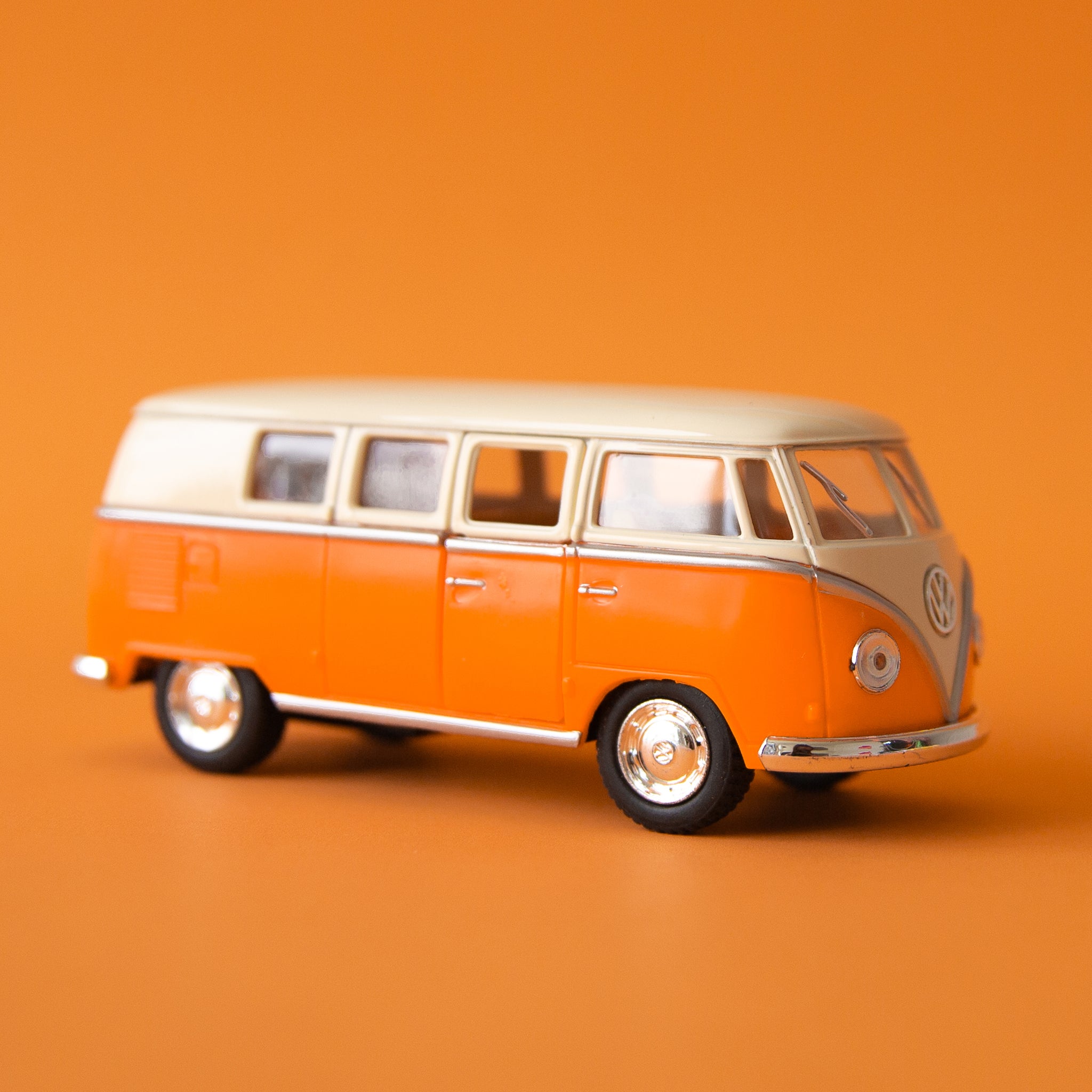 On an orange background is an orange and white VW bus toy