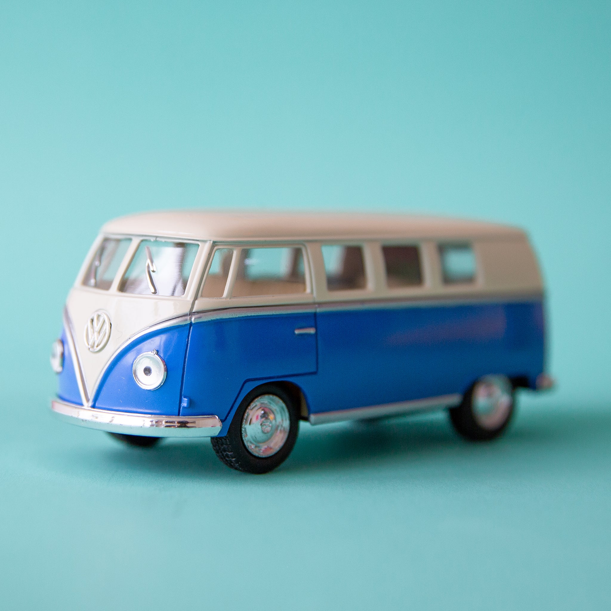 On a blue background is a blue and white VW bus toy.