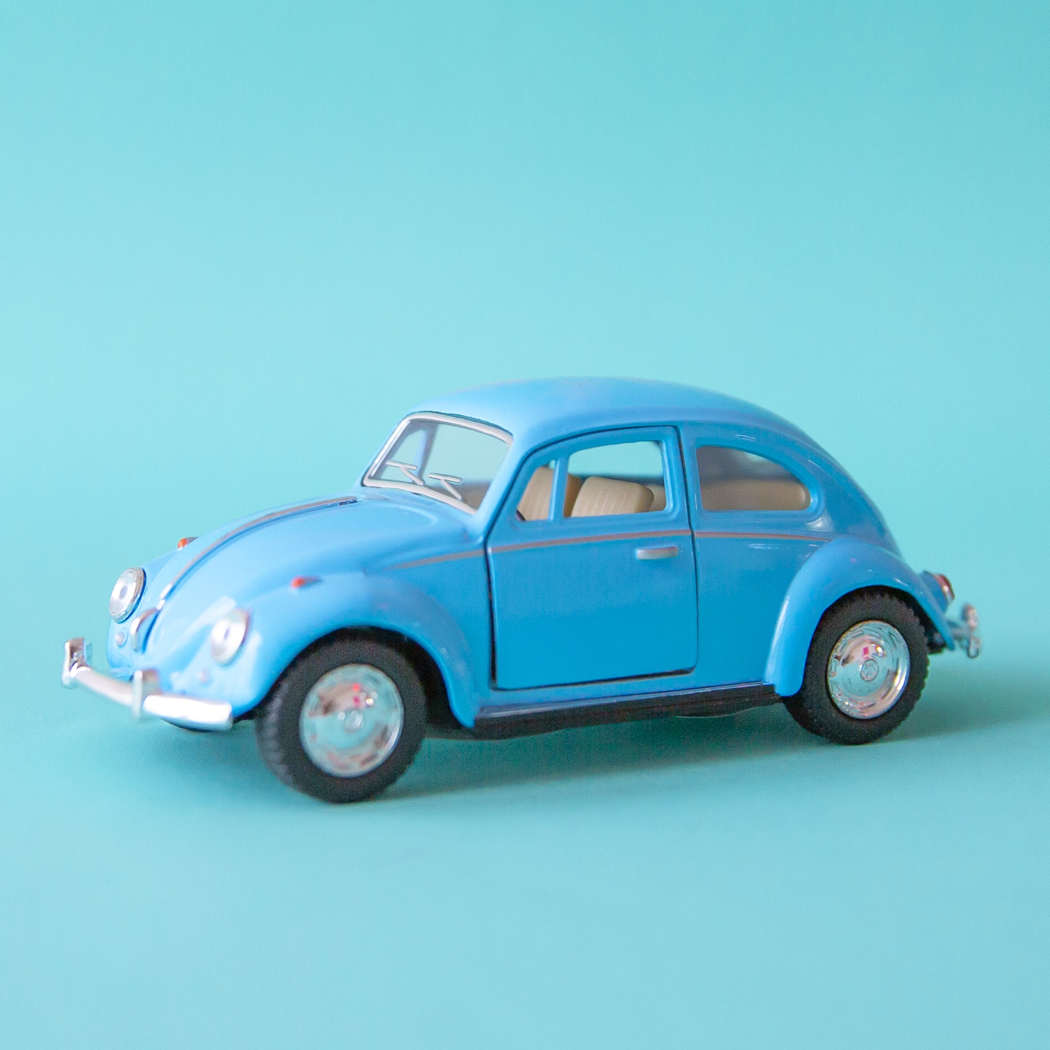 On a blue background is a blue VW beetle toy car. 