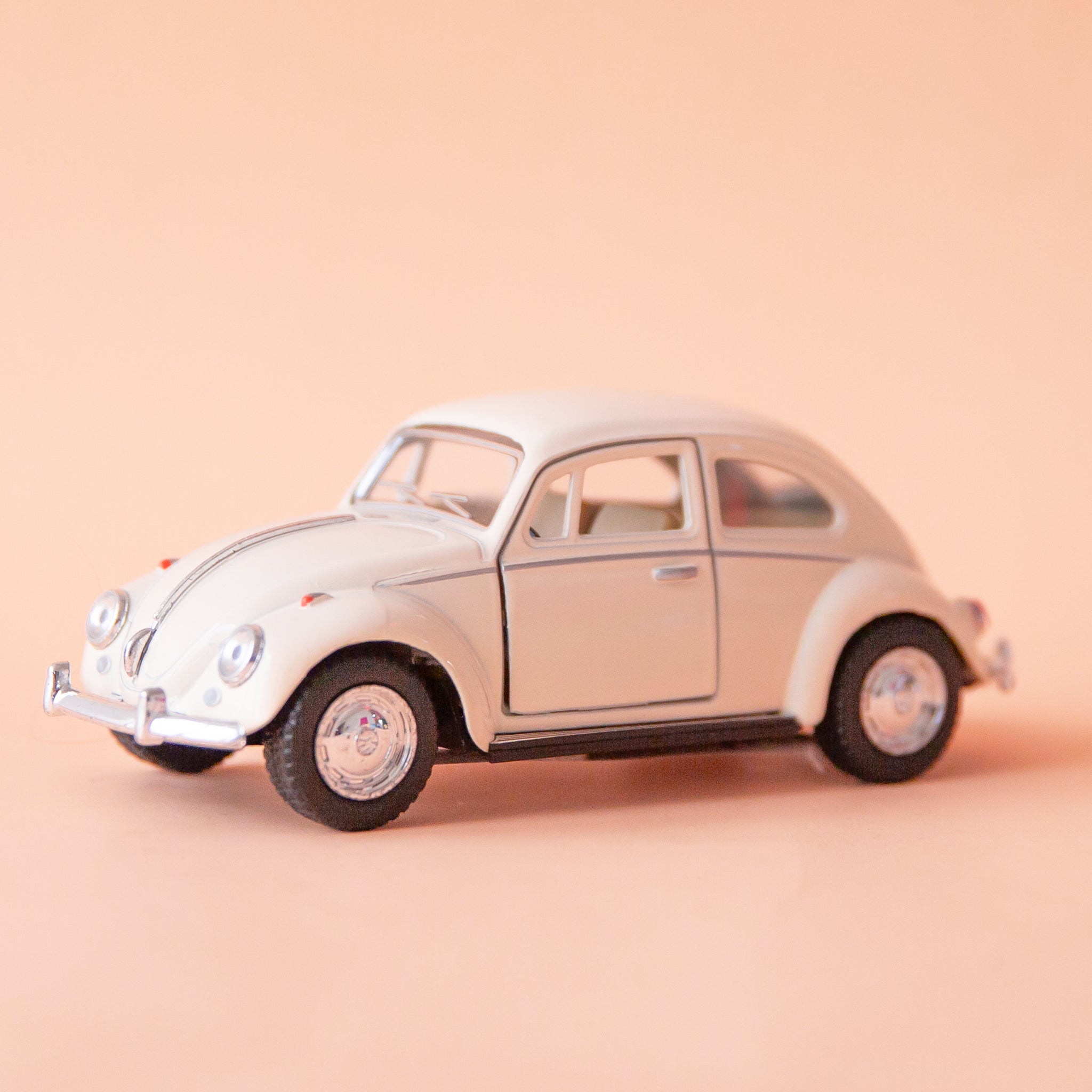 On a tan background is a white beetle toy car. 