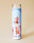 On a tan background is a blue prayer candle with a photo of Ken played by the actor Ryan Gosling.