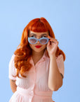On a blue background is a model wearing the Gemma Sunglasses in the shade Lapis.