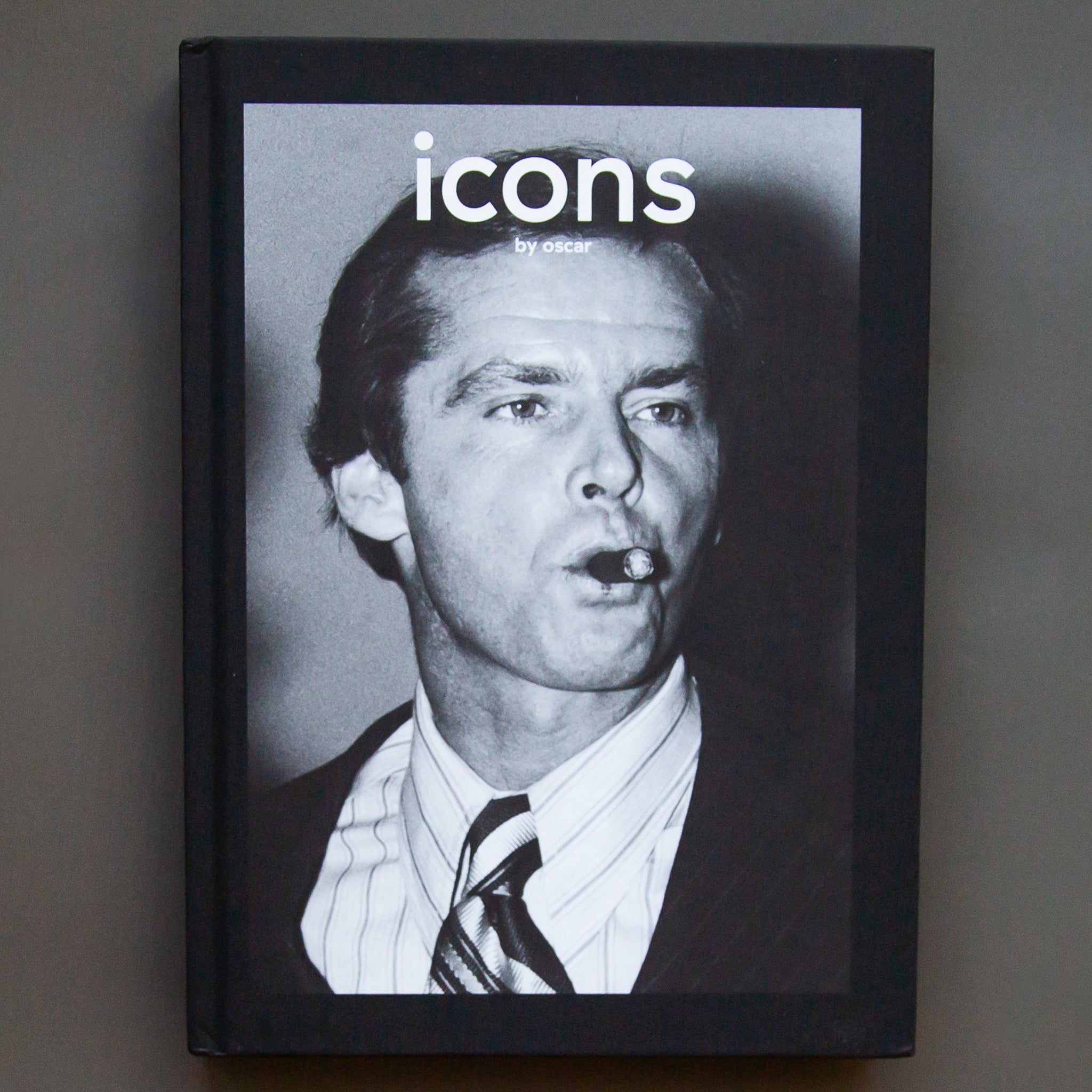 On a grey background is a black and white book with a photo on the front and the title in white that reads, &quot;icons by oscar&quot;. 