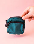 A cypress green colored fanny pack bag charm with black zippers and details.