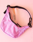 A small crescent bag charm in a pink shade with black straps and zipper.