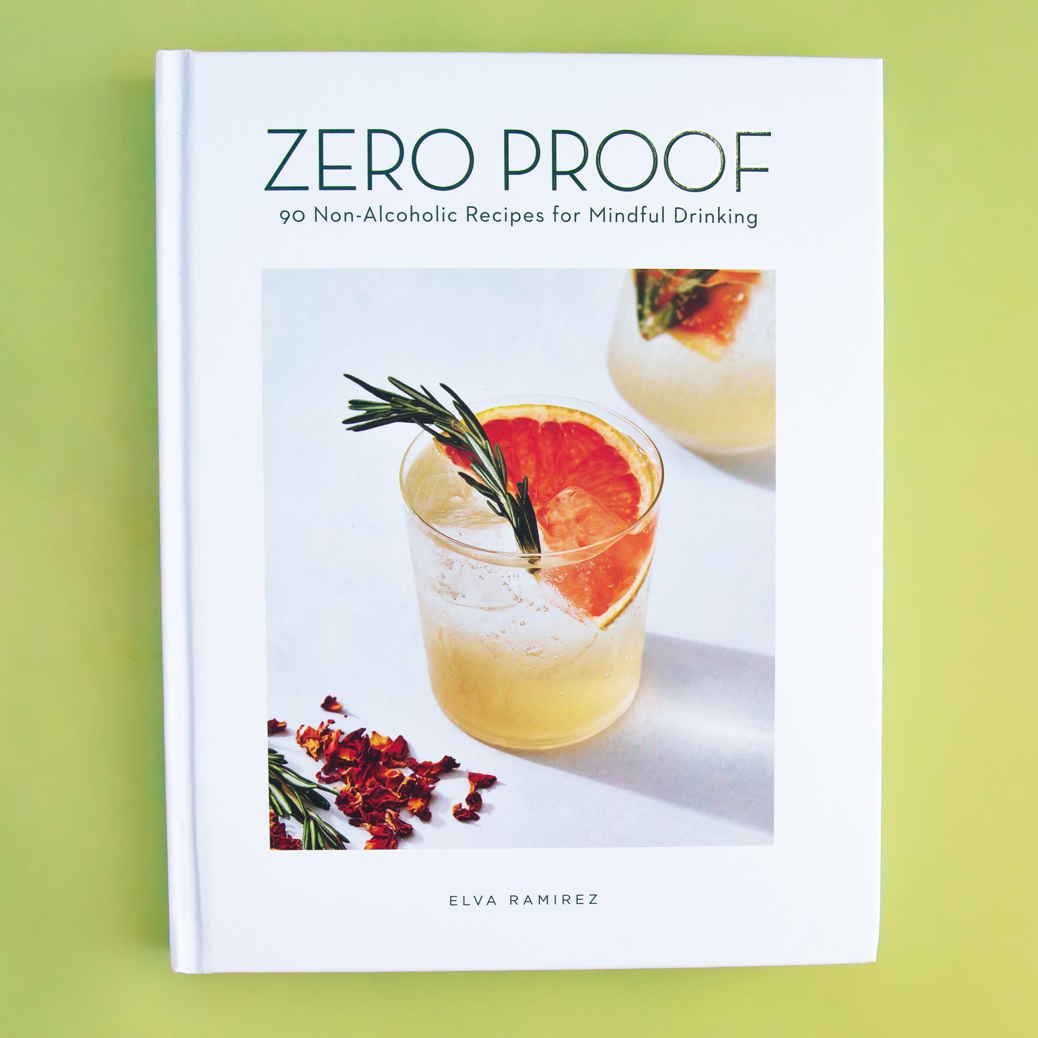 On a green background is a white book with a cocktail photo on the front and the title at the top that reads, &quot;Zero Proof 90 Non-Alcoholic Recipes for Mindful Drinking&quot;. 