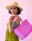 On a pink background is a hot pink woven bag.
