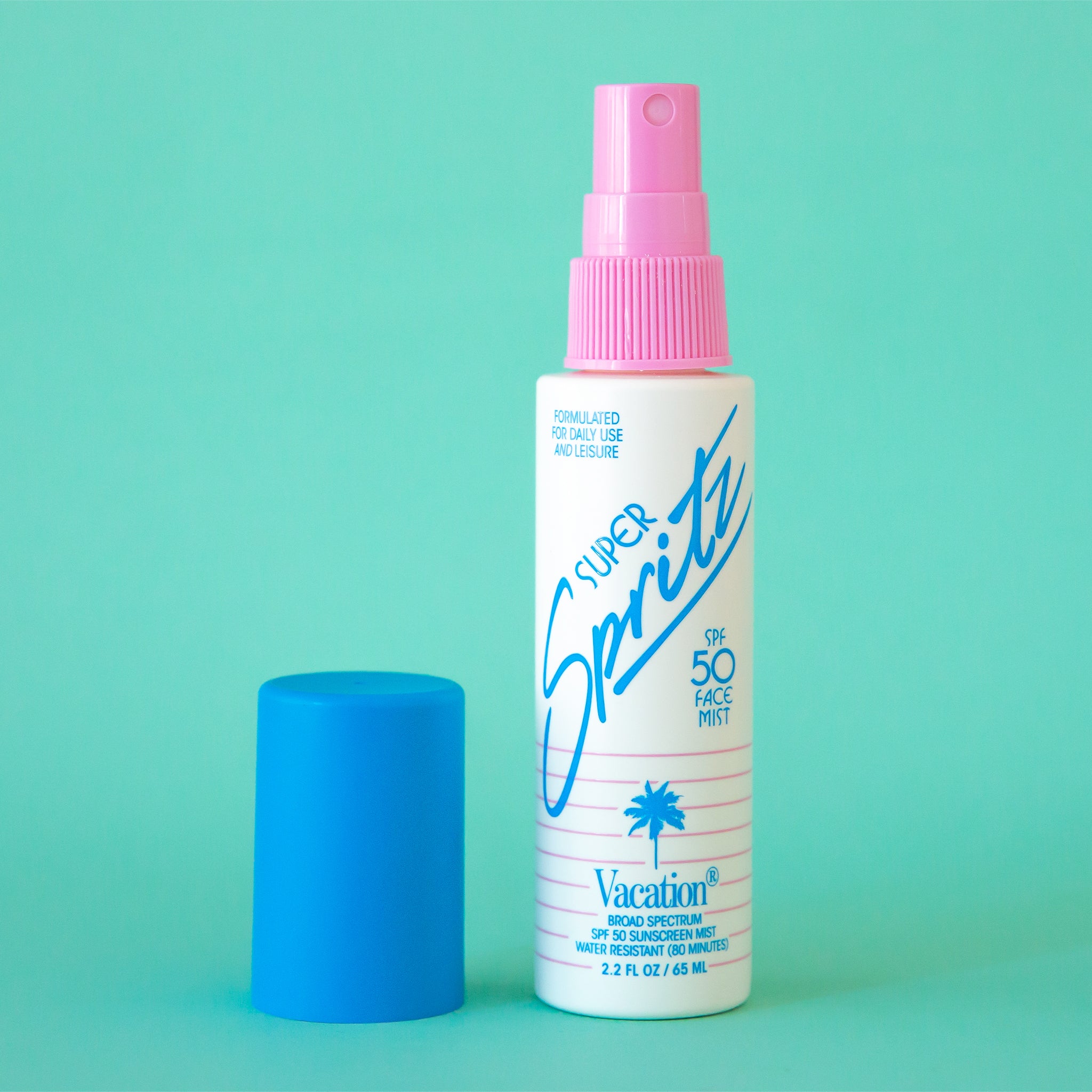 On a blue background is a spray bottle of facial mist with a white bottle, pink spray and blue cap. The text on the bottle reads, &quot;Super Spritz&quot; in blue letters.