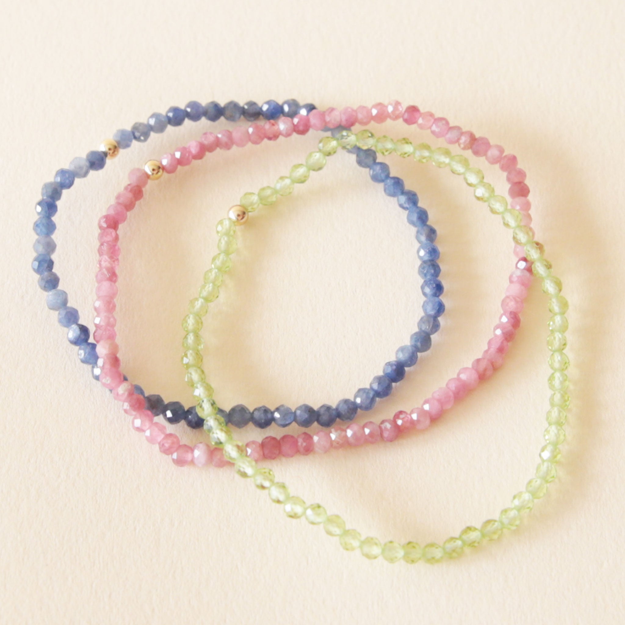 Three different colored beaded bracelets. One blue, one pink and one green. 