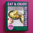 On a purple background is a green and purple book cover with a photo of food on the front and the title around the edges that reads, "Eat & Enjoy Gluten Free". 