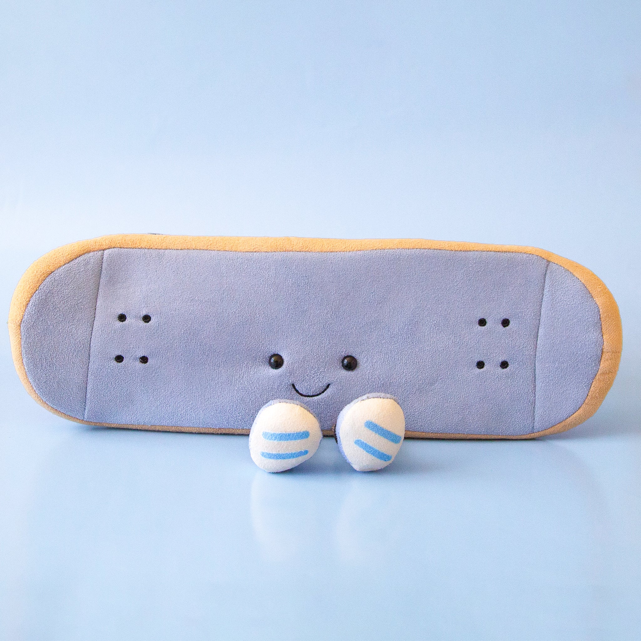 A skateboard shaped stuffed toy with small legs and feet and a smiling face