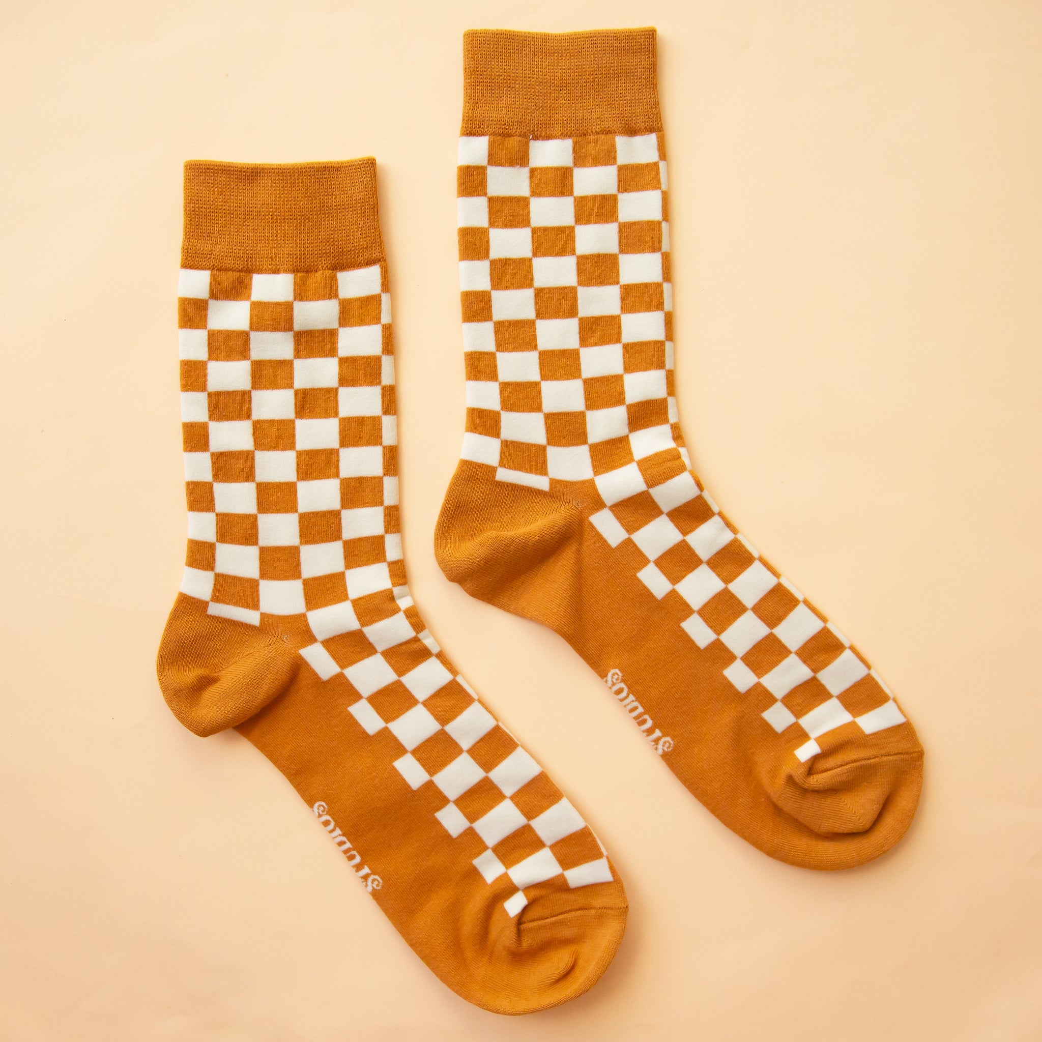 A burnt orange and white checker print pair of socks. 