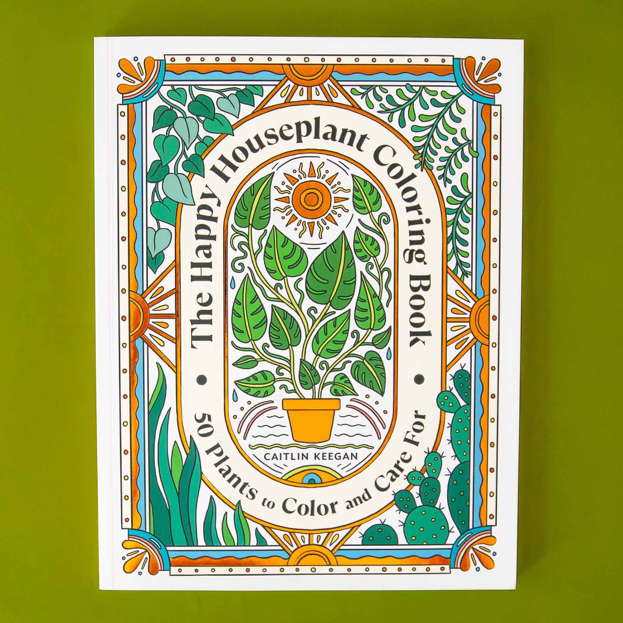On a green background is a green and orange coloring book with illustrations of house plants and text arched around that reads, &quot;The Happy Houseplant Coloring Book&quot;, &quot;50 Plants to Color and Care For&quot;. 