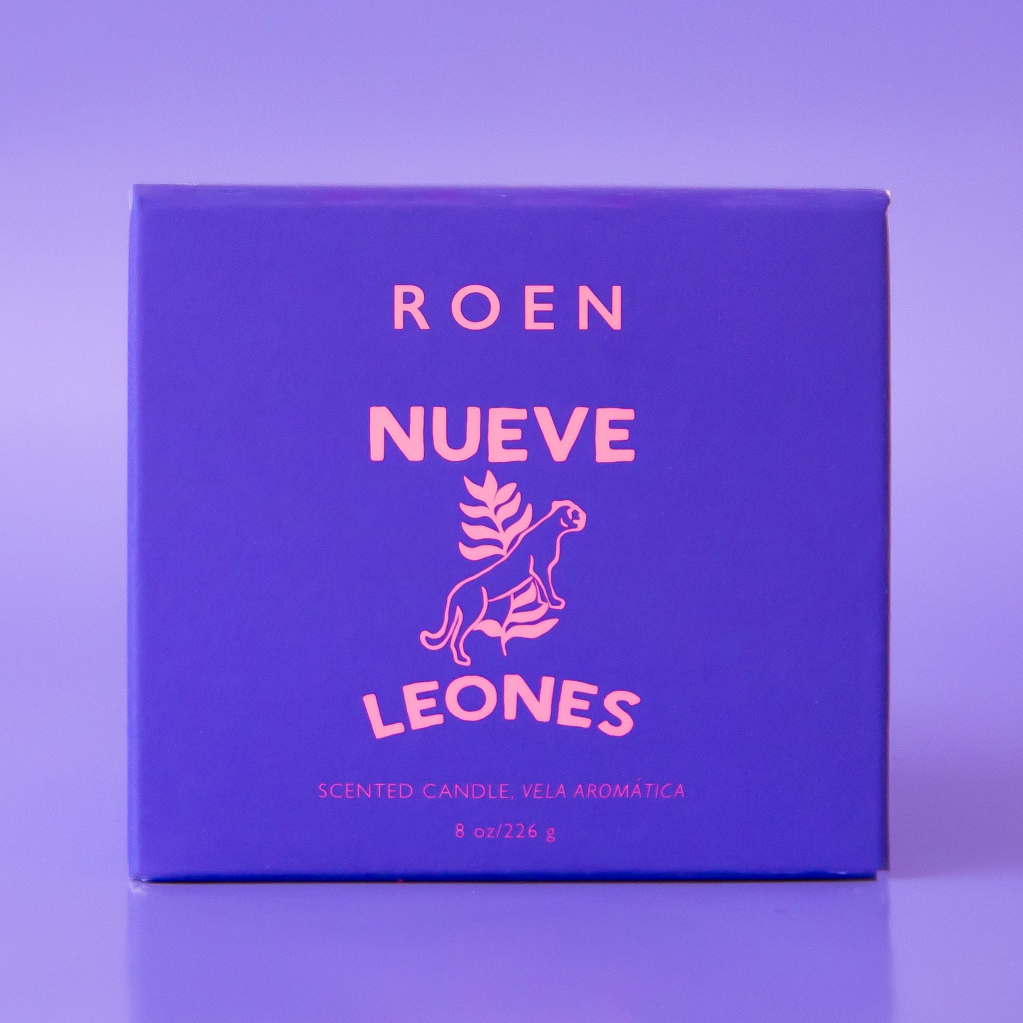 A purple glass candle with a white label with, "Nueve Leones".
