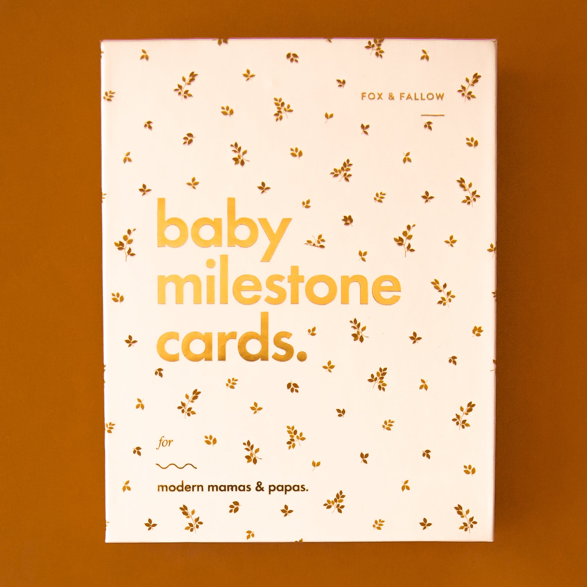 On a burnt orange background is a neutral box with text that reads, &quot;baby milestone cards.&quot;. 