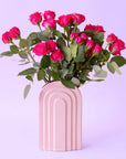 An arched ceramic vase in a cool toned pink shade.